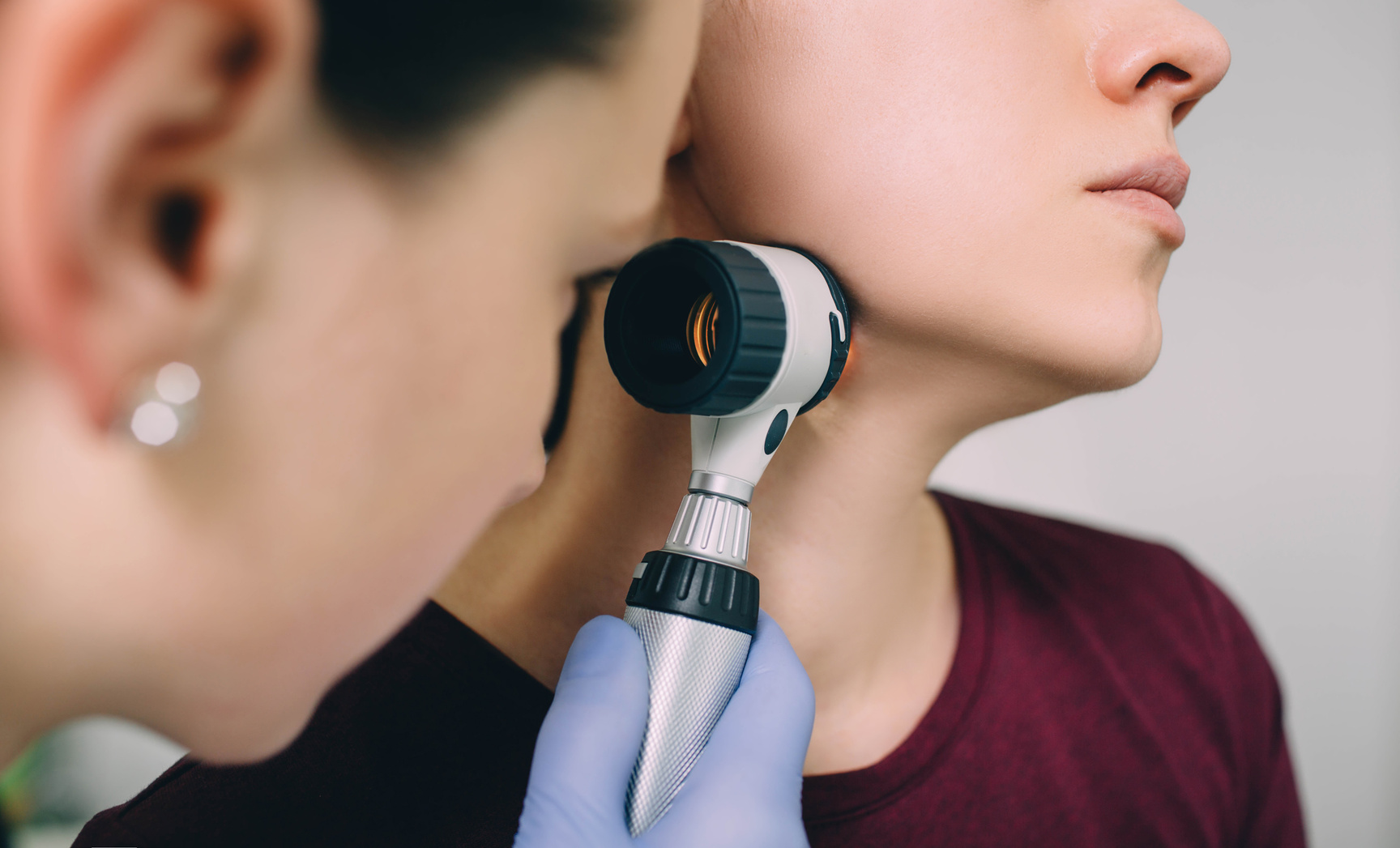 dermatologist exam patient's skin using dermatoscope at clinic